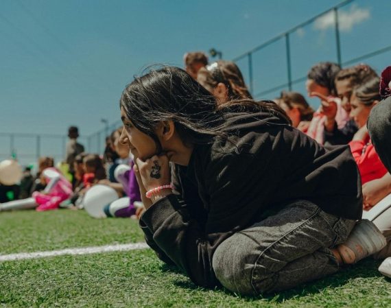 Smiling girls sitting on football field