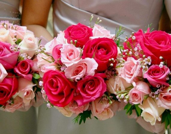 Three women holding bouquets of pink and red hybrid tea roses