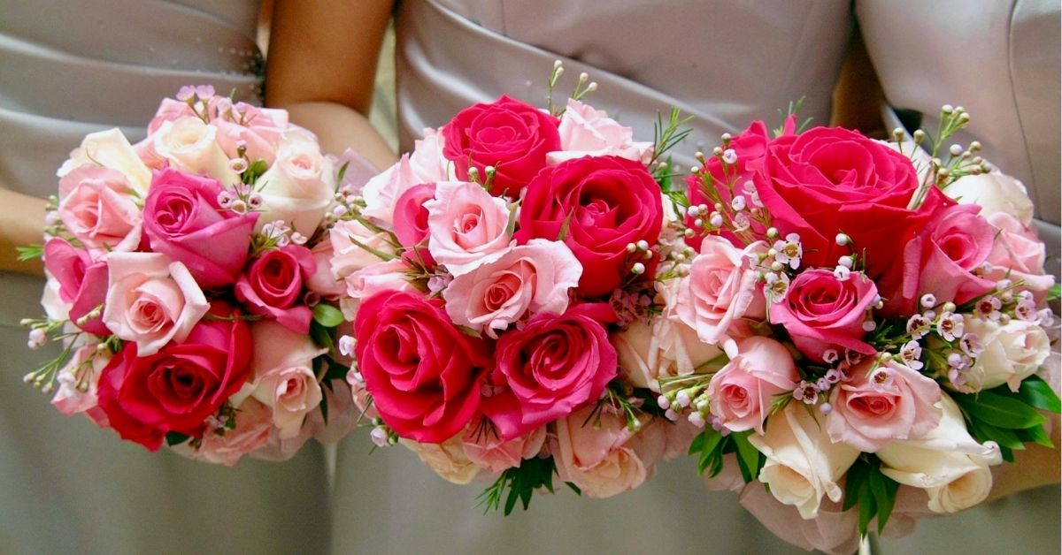 Three women holding bouquets of pink and red hybrid tea roses